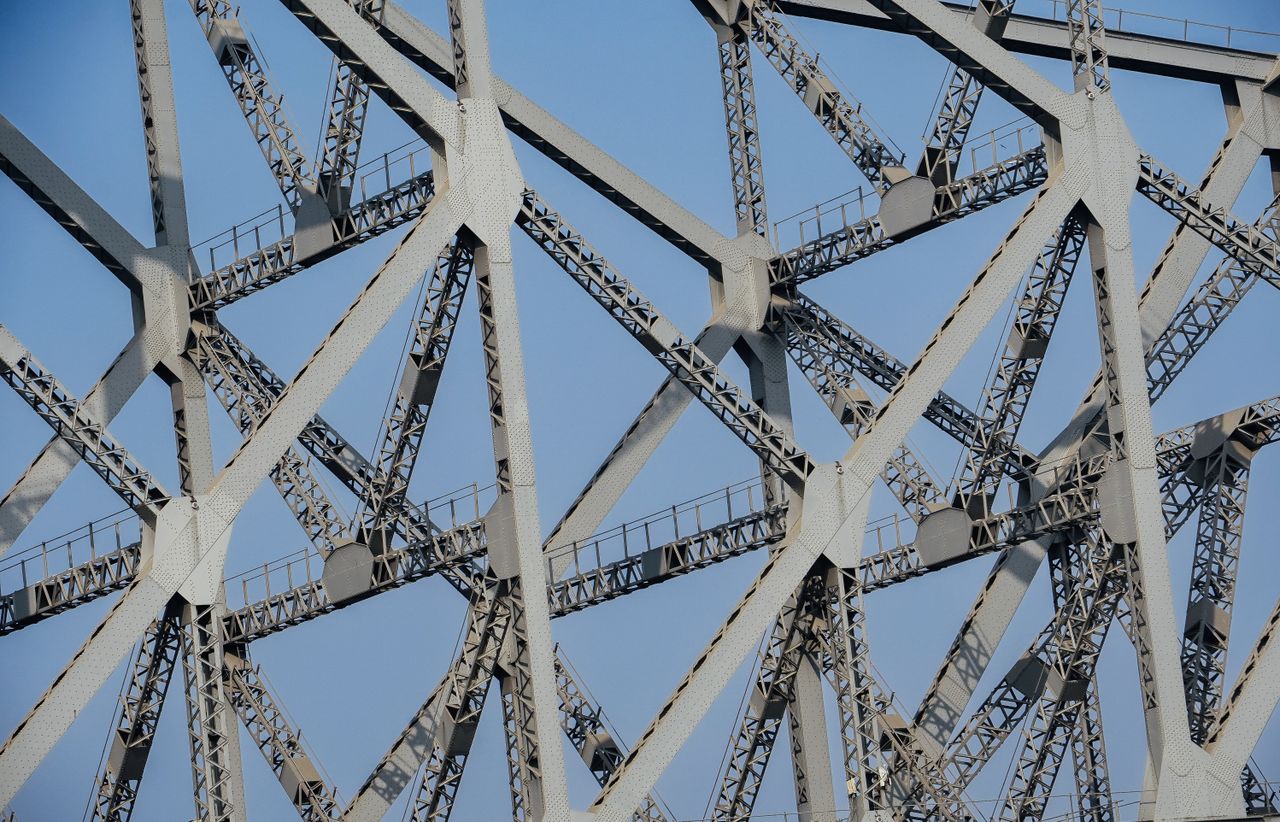 Detailed view of intersecting steel beams of a bridge against a clear sky.